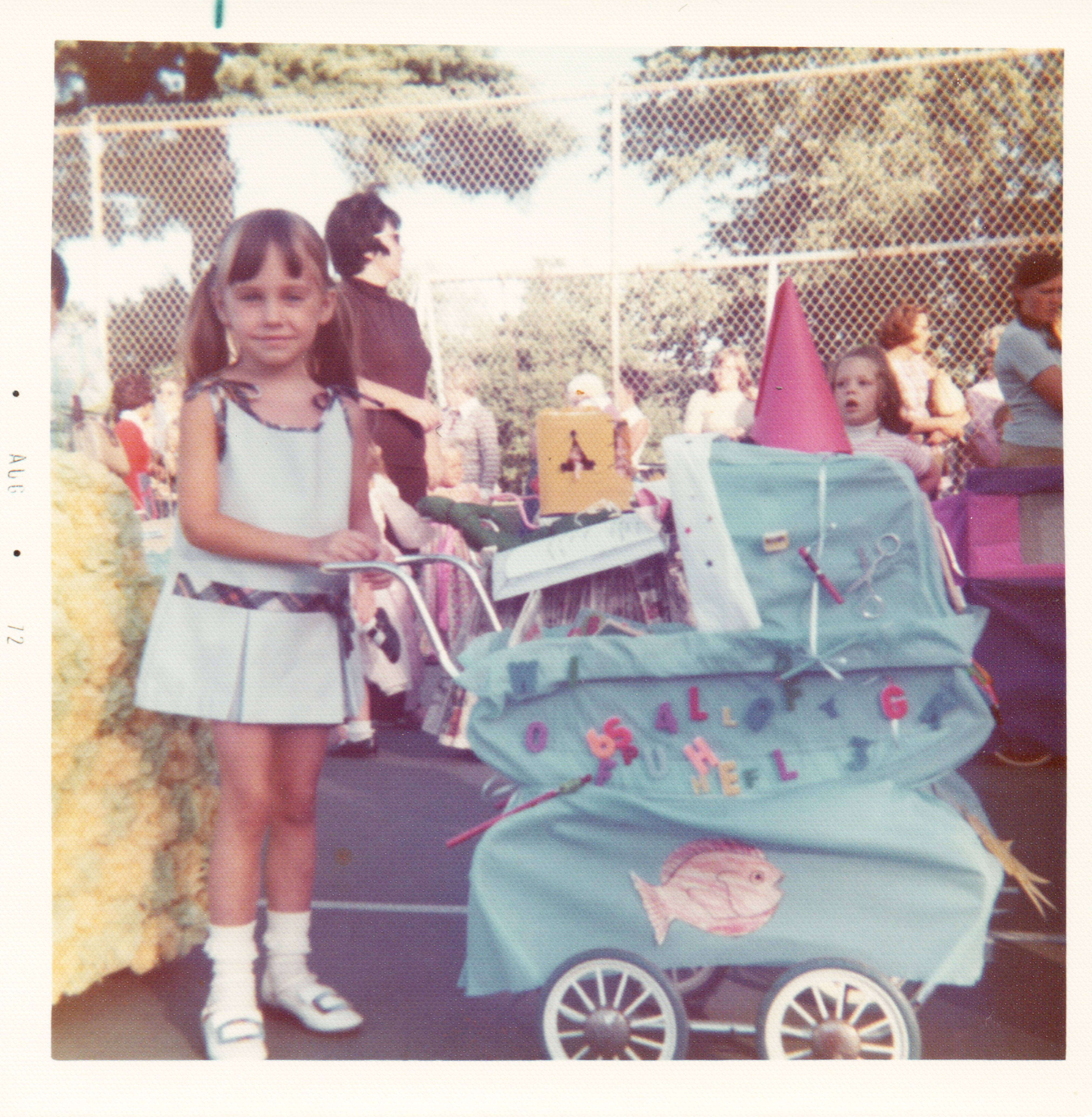 A photo of a girl with a decorated doll carriage.